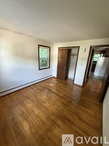 A room with wooden floors and a window with a view of trees.