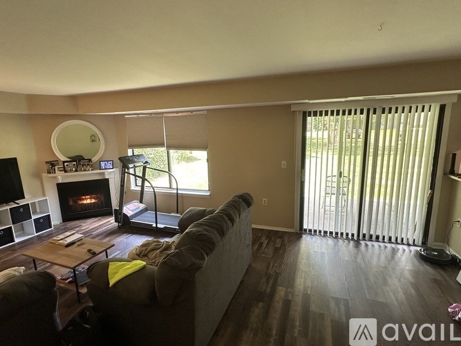 A living room with a fireplace and a grey couch.