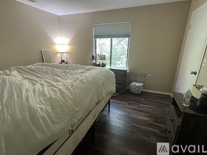 A bedroom with a large bed and a window with blinds.