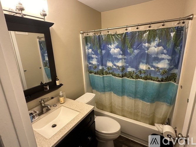 A bathroom with a sink, toilet, and a shower curtain with a tropical print.