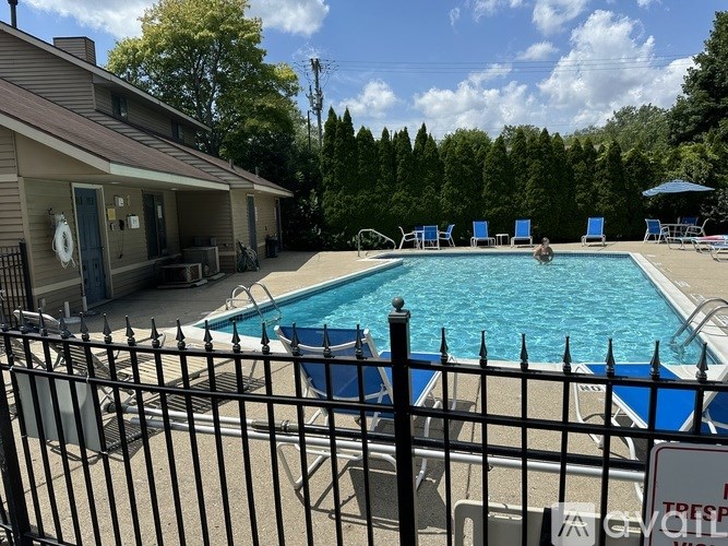A pool surrounded by a black fence and blue chairs.