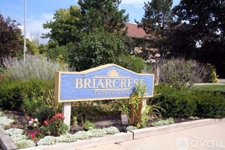 A sign that says Briarcrest Condos in front of some trees.