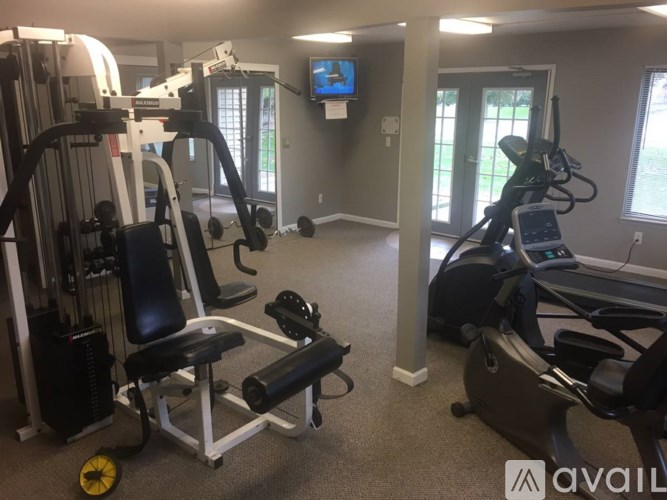 A gym with a variety of equipment including treadmills, weights, and a television.