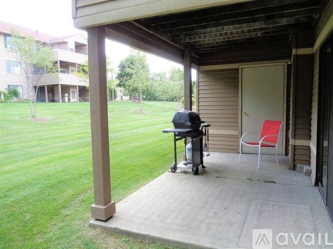 A covered porch with a chair and a grill on it.