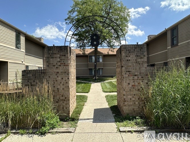 A brick archway leads to a courtyard between two apartment buildings.