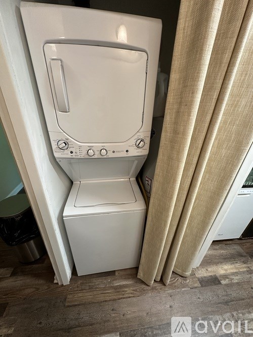A white toilet with a beige curtain in front of it.