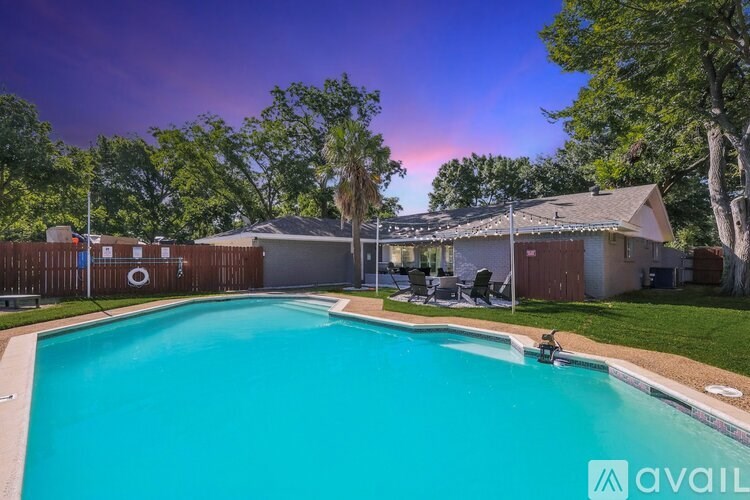 A swimming pool in a backyard with a house and trees in the background.