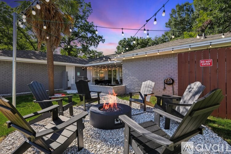 A patio with chairs and a fire pit is set up outside a house.