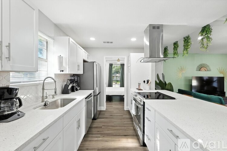A modern kitchen with white cabinets and a green backsplash.