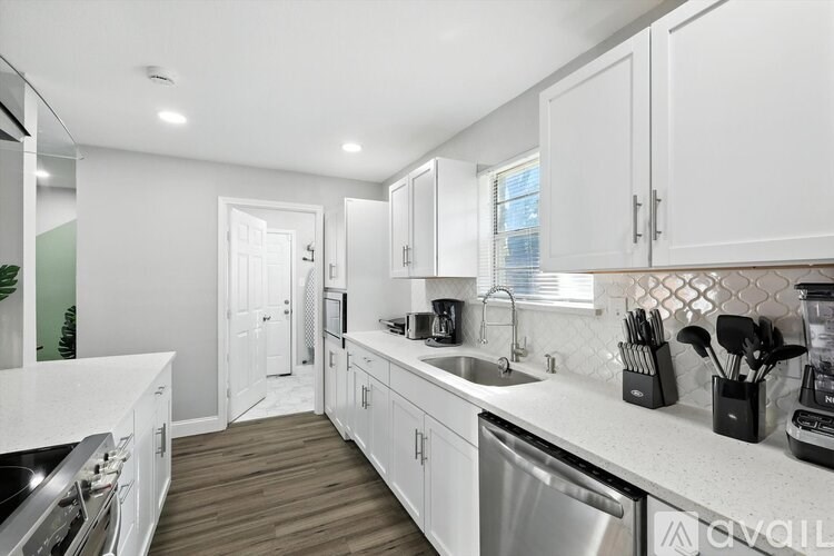 A kitchen with white cabinets and a wooden floor.