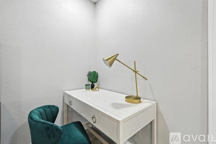 A white desk with a green chair and a gold desk lamp.