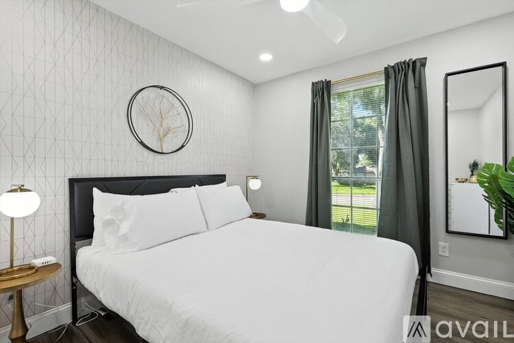 A bedroom with a large bed, a round mirror, and a wall clock.