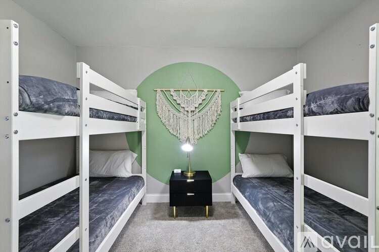 A room with white bunk beds and a green wall.