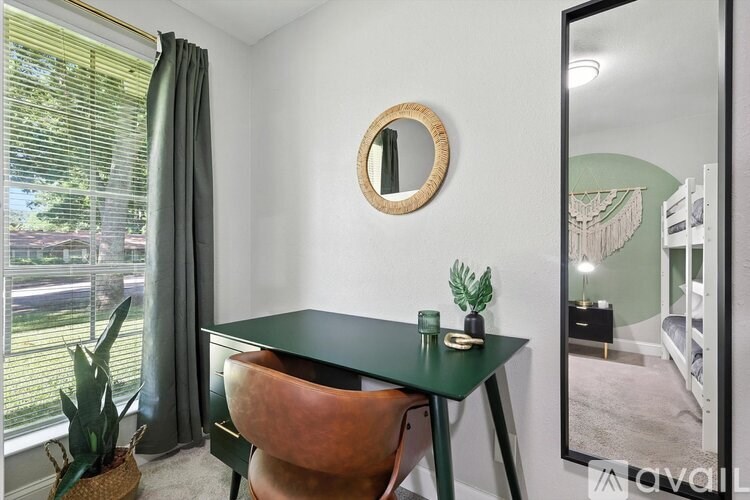 A room with a green table and a round mirror on the wall.