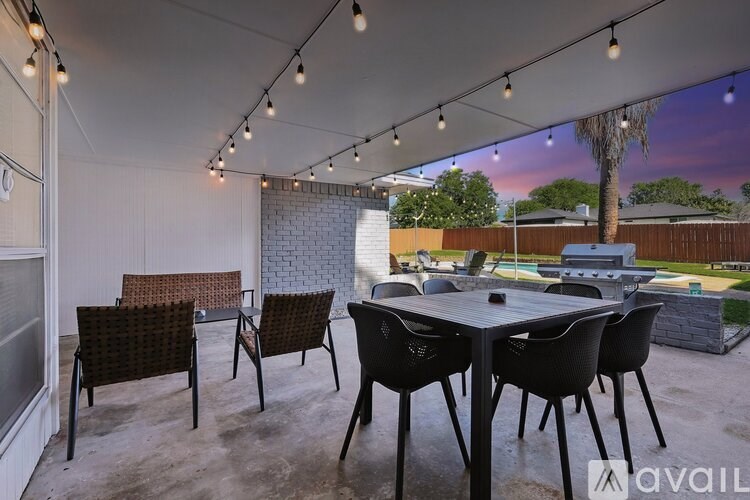 A patio with a table and chairs under string lights.