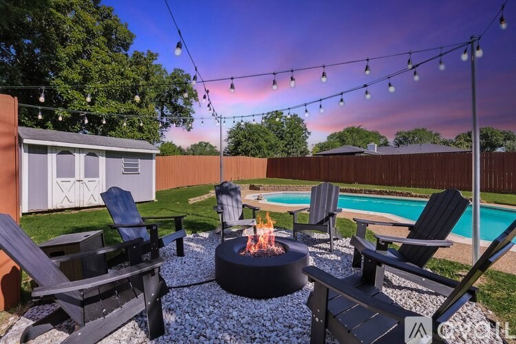 A backyard with a fire pit and chairs.
