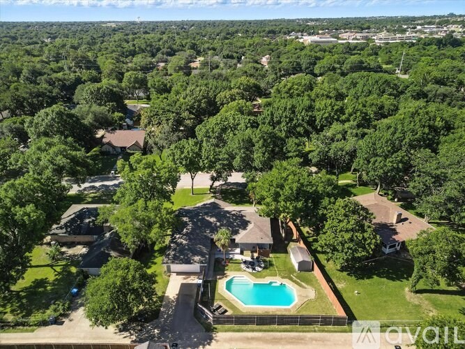 A bird's eye view of a residential area with a swimming pool surrounded by trees.