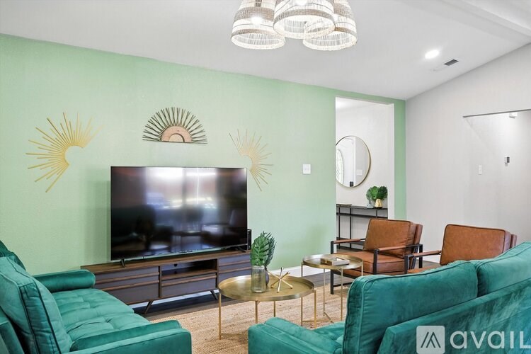 A living room with a television, two chairs, a coffee table, and a mirror.