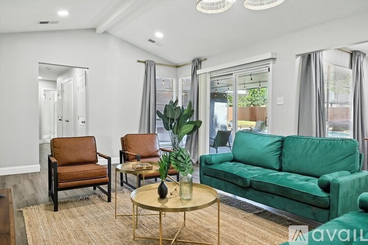 A living room with a green couch, a coffee table, and two chairs.