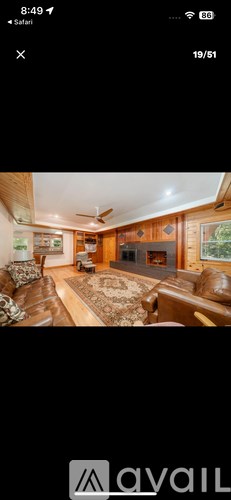 A living room with a brown leather couch and a rug.