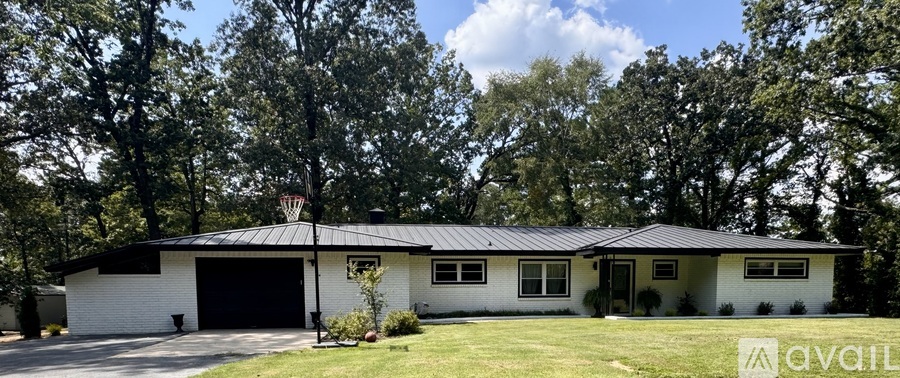 A white house with a metal roof is surrounded by trees.