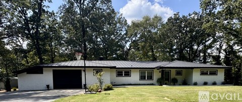 A white house with a metal roof is surrounded by trees.