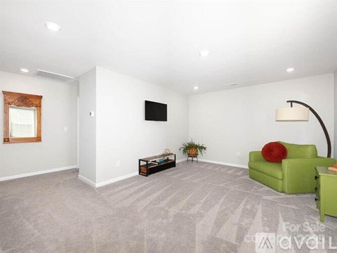 A living room with a green couch and a flat screen TV mounted on the wall.