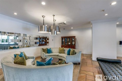 A living room with a white couch and a black leather ottoman.
