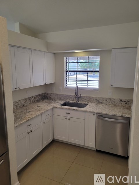 A kitchen with white cabinets and a granite countertop.