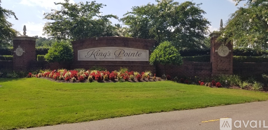 A sign that says King's Pointe in front of a wall with flowers.