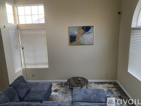 A living room with a blue couch, a small table, and a painting on the wall.