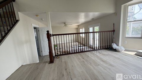 A spacious living room with a staircase on the left and a window on the right.