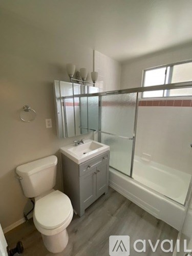 A bathroom with a toilet, sink, and shower.