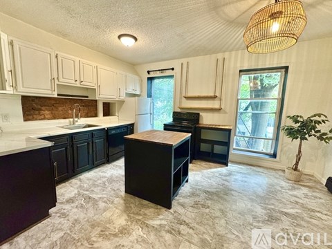 A kitchen with black cabinets and a wooden island.