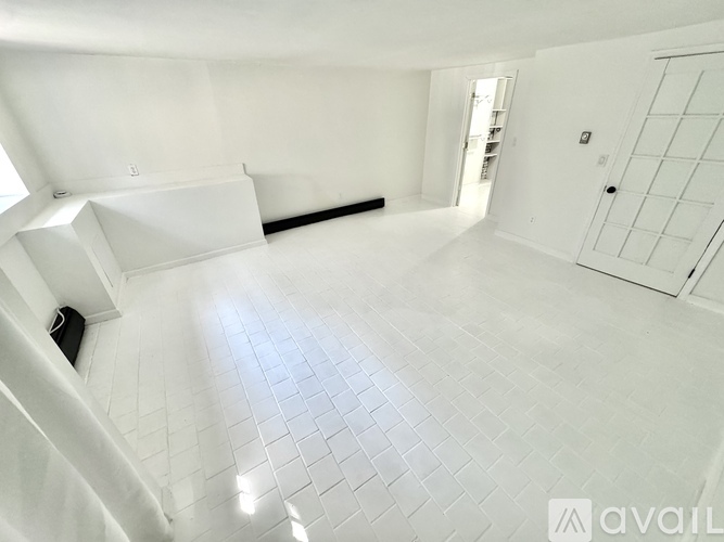 A spacious room with white tiled flooring and white walls.