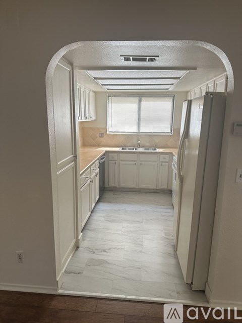 A kitchen with white cabinets and a refrigerator.