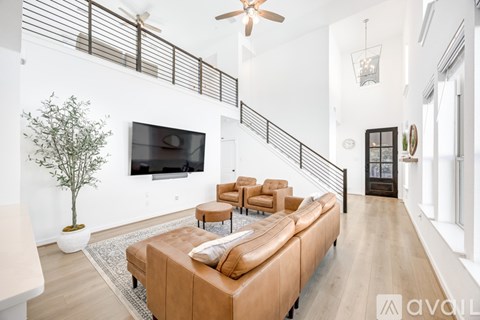 A living room with a brown couch and a television on the wall.
