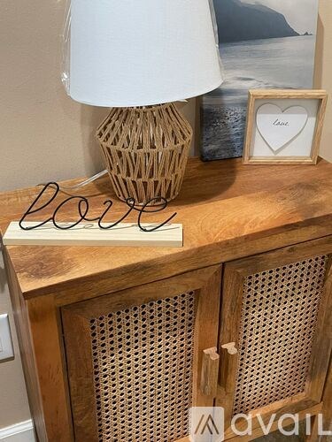 A wooden cabinet with a lamp and a heart-shaped frame on top.