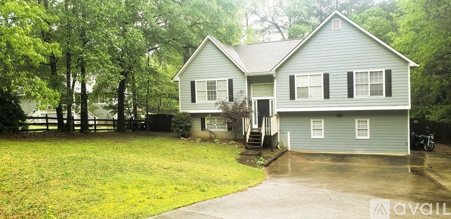 A house with a grey siding and a white window is surrounded by trees.