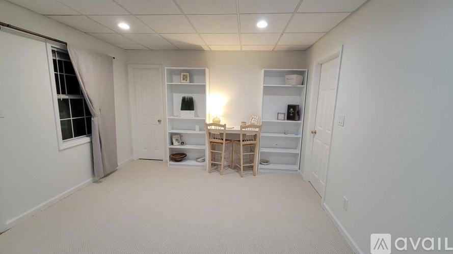 A room with a table and chairs in the middle, and shelves on the walls.