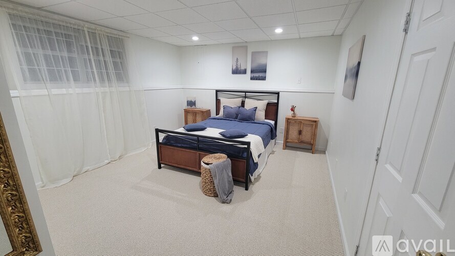 A bedroom with a bed, a nightstand, and a window with curtains.