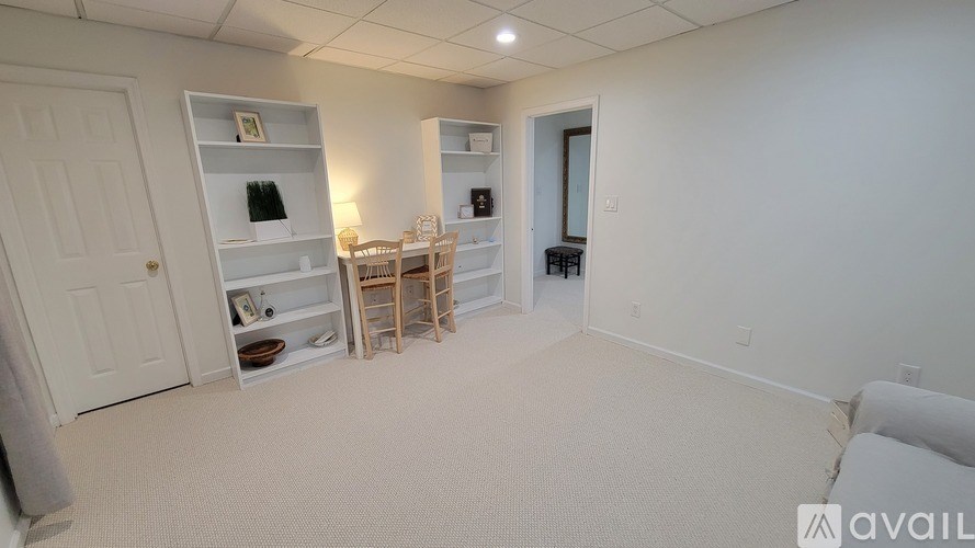 A room with a white door, a white couch, and a white shelf with various items on it.