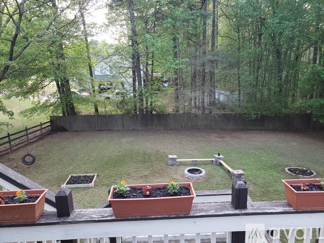 A backyard with a fence, a lawn, and potted plants.
