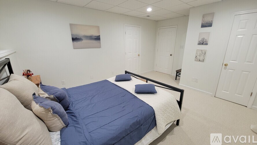 A bedroom with a bed, pillows, and pictures on the wall.