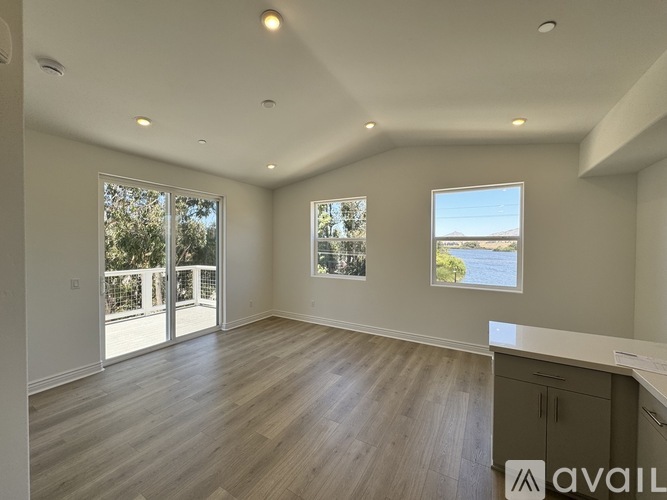 A spacious room with wooden floors and a large window overlooking a body of water.