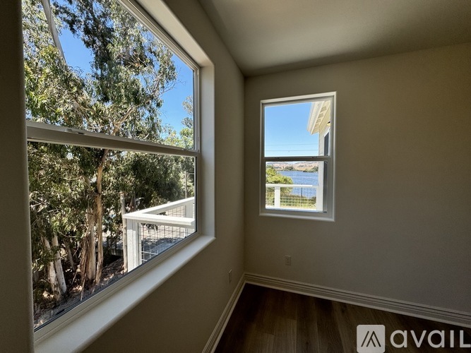 A room with a view of a deck and trees through a window.