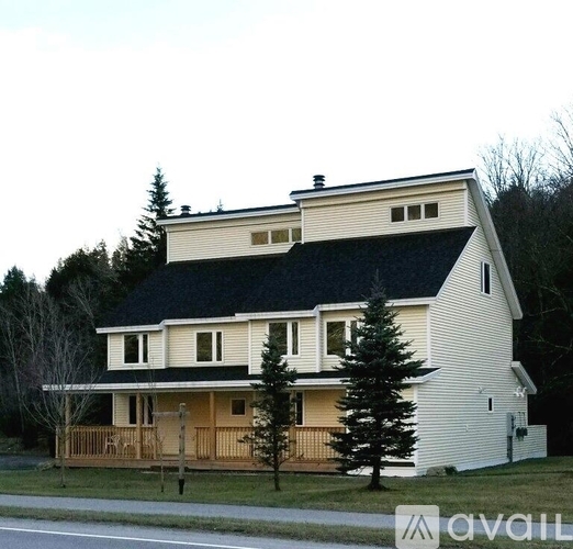 A white house with a black roof and a balcony.