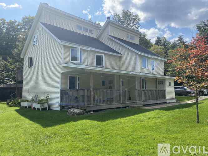 A two-story house with a porch and a balcony is for sale.