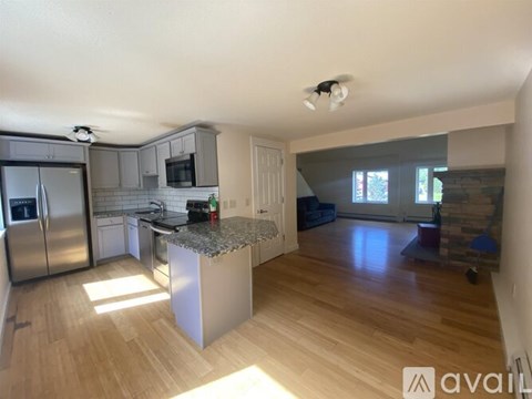 A kitchen with a refrigerator, microwave, and a countertop with a sink.