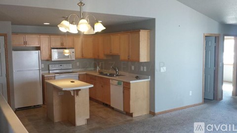 A kitchen with wooden cabinets and a white fridge is available for rent.